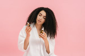 Woman with curly hair examining two cosmetic oil bottles