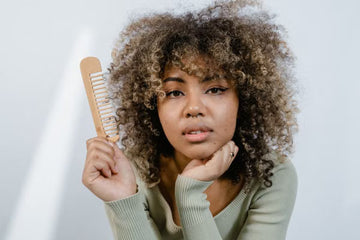 Woman with natural curls holding a wide-tooth comb