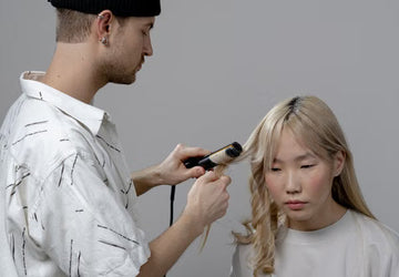 Stylist using a curling iron on a client's hair in a salon