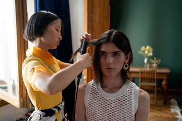 Hairdresser styling a client's hair with a flat iron