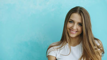 Woman with long hair smiling against a pale blue backdrop