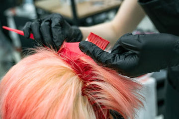 Gloved hands applying vibrant colour to hair