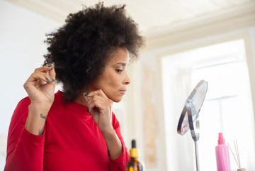 Woman styling her thick curls at a mirror