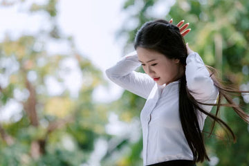 Young woman adjusting her hair outdoors in sunlight