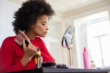 Woman styling her curls at a mirror at home