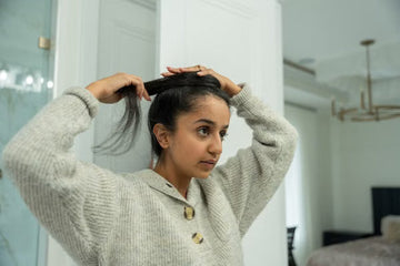 Young woman styling her hair into a bun in a bathroom